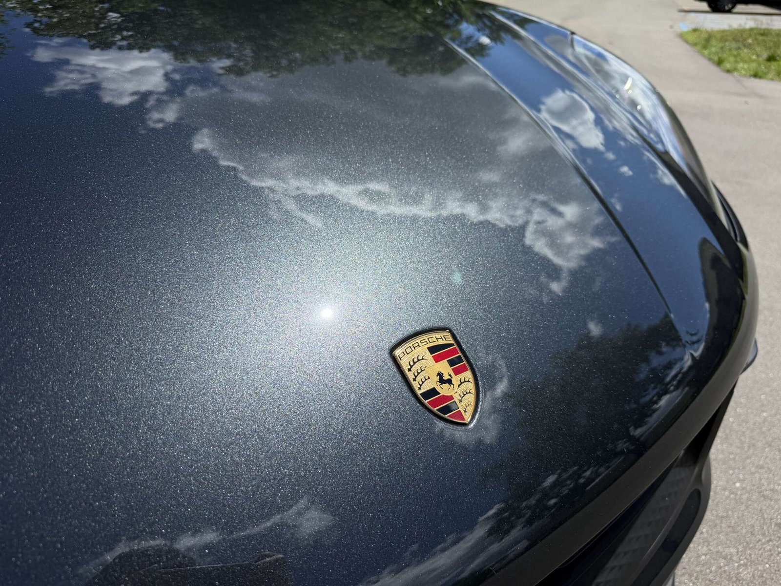 Ceramic-Coating-Porsche-Hood-Detail Close-up of a Porsche crest and hood after ceramic coating, showing paint clarity and reflection